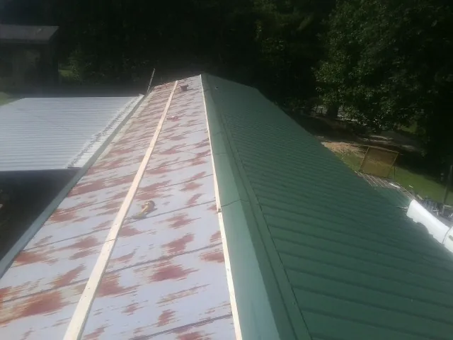 Old rusted panels beside newly installed green metal roofing — Wind Damage Roof Repair by Roofing Brothers in South Ozone Park