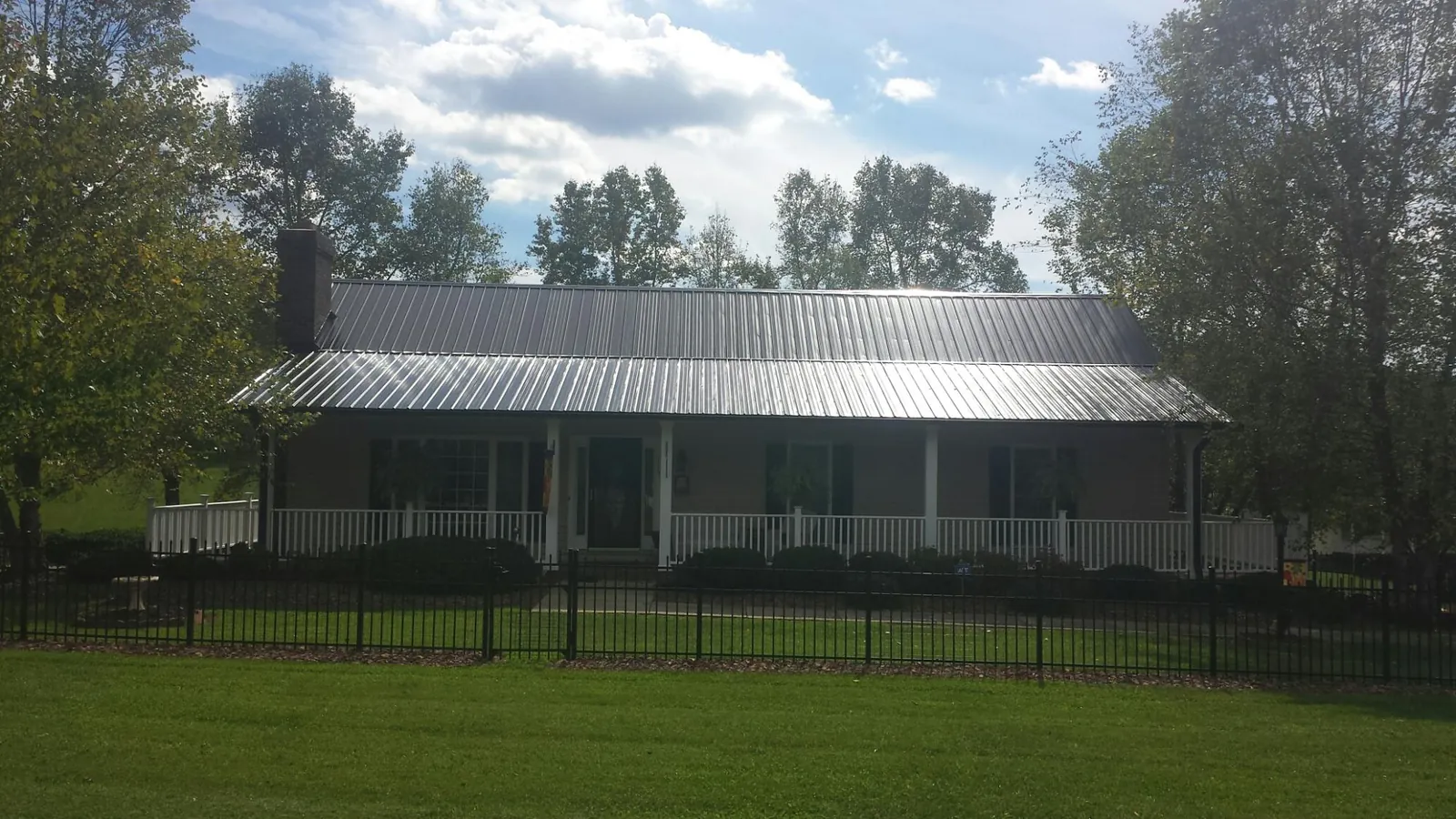 Gray metal roof on a brick ranch with a full width front porch — Gutter Guard Installation work by our crew in South Ozone Park