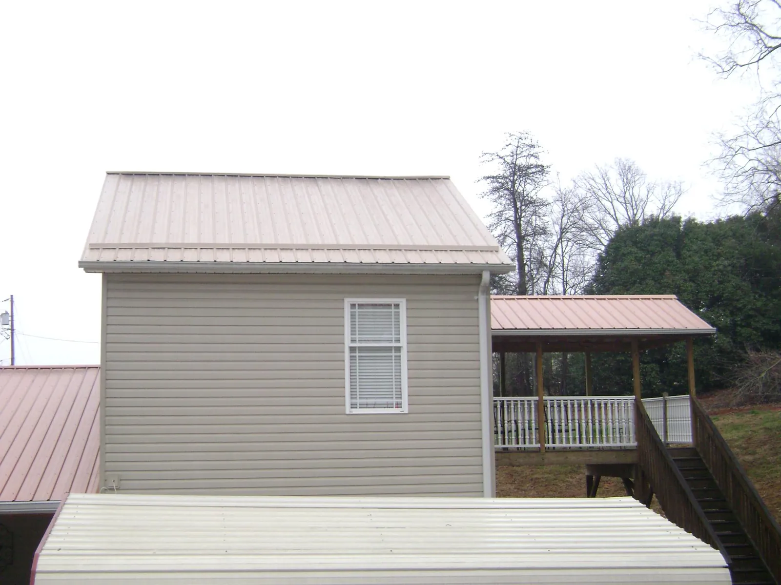 Tan metal roofs on a two story addition and attached porch, from a Roof Replacement job in South Ozone Park